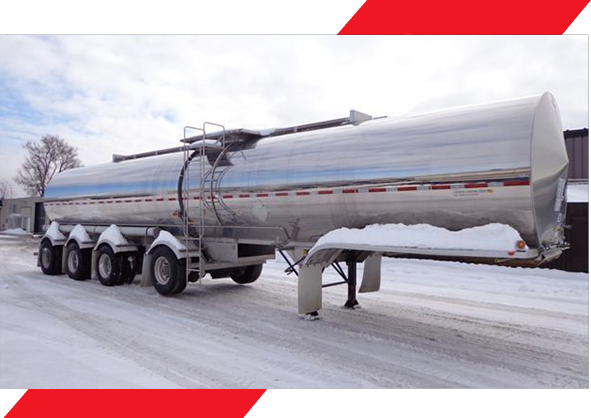 A tanker truck driving down the road in winter.