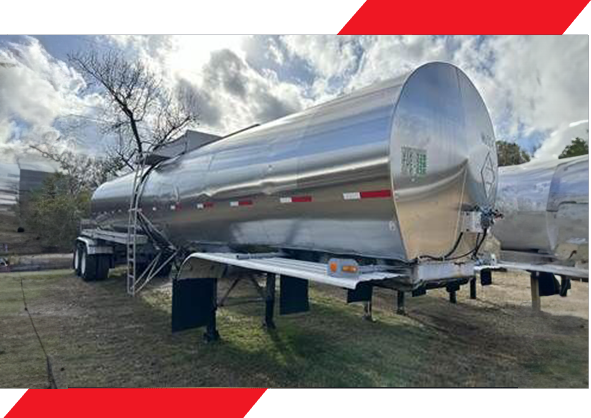 A large silver tanker truck parked on the side of road.