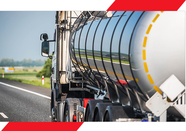 A tanker truck driving down the road near a field.