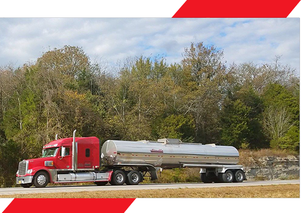 A red truck with a silver tanker trailer on the road.